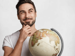 Un ragazzo che con faccia perplessa ma sorridente tiene in mano un mappamondo