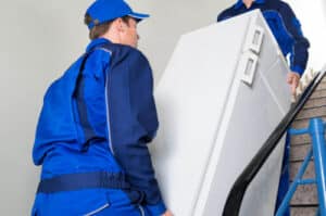 Due traslocatori che trasportano un frigorifero per delle scale condominiali